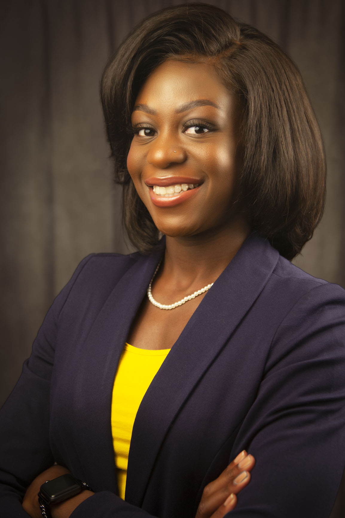 Studio headshot of a smiling woman in a purple blazer and yellow top