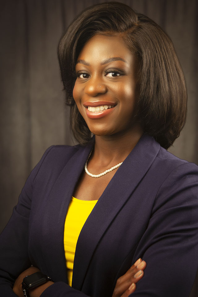 Studio headshot of a smiling woman in a purple blazer and yellow top