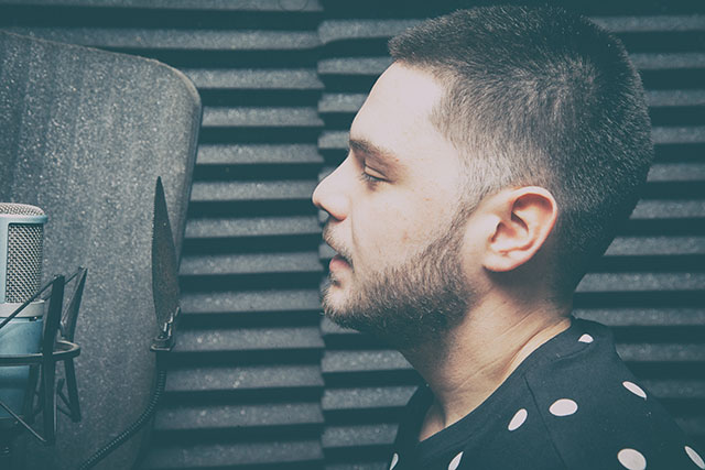 Side-profile portrait of a vocalist at a studio microphone