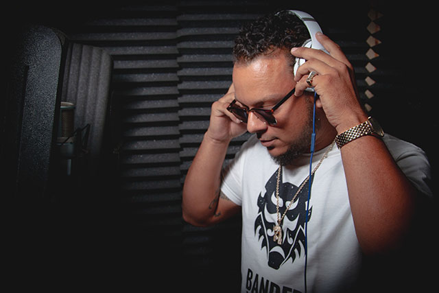 Portrait of a DJ adjusting headphones in a recording booth