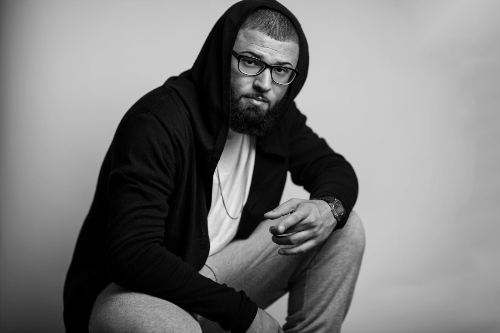 Black-and-white editorial portrait of a man in a hoodie