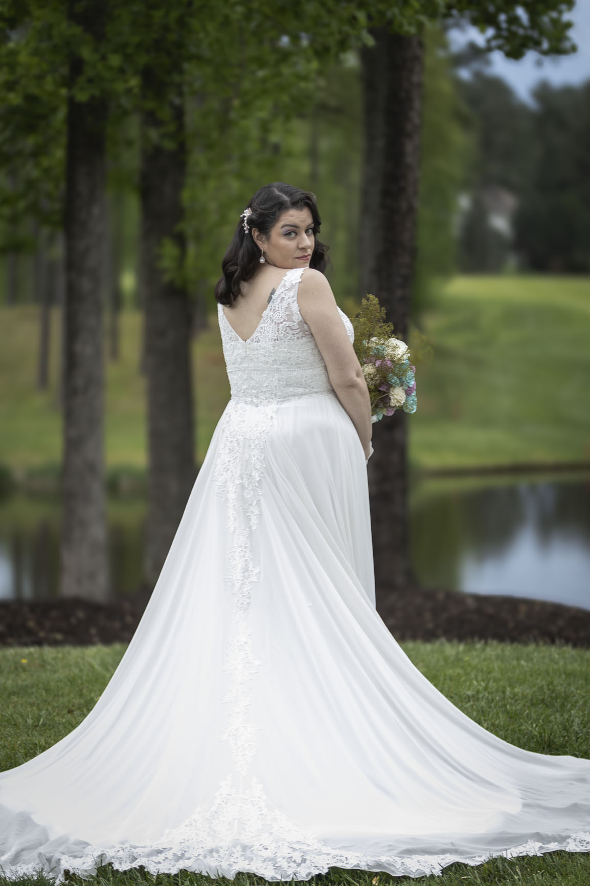 Wedding portrait of a bride beside a pond with her gown train extended